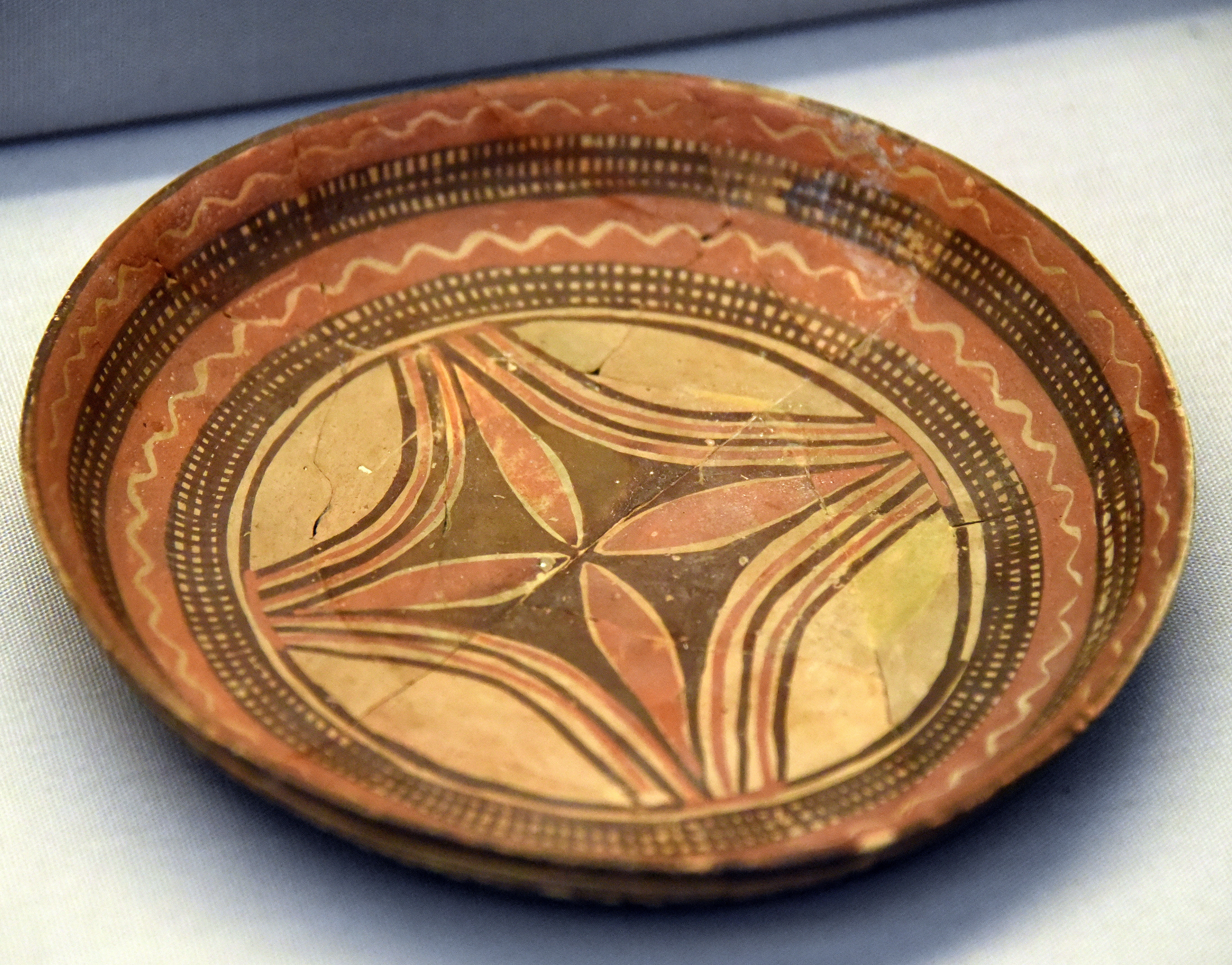 FileHandmade_pottery_shallow_plate._The_interior_is_decorated_with_a_floral_design_in_the_center_with_polychrome_in_black_and_red_on_the_buff_surfaces._From_Tell_Arpachiyah_Iraq._Halaf_period_6000-5000_BCE.jpg